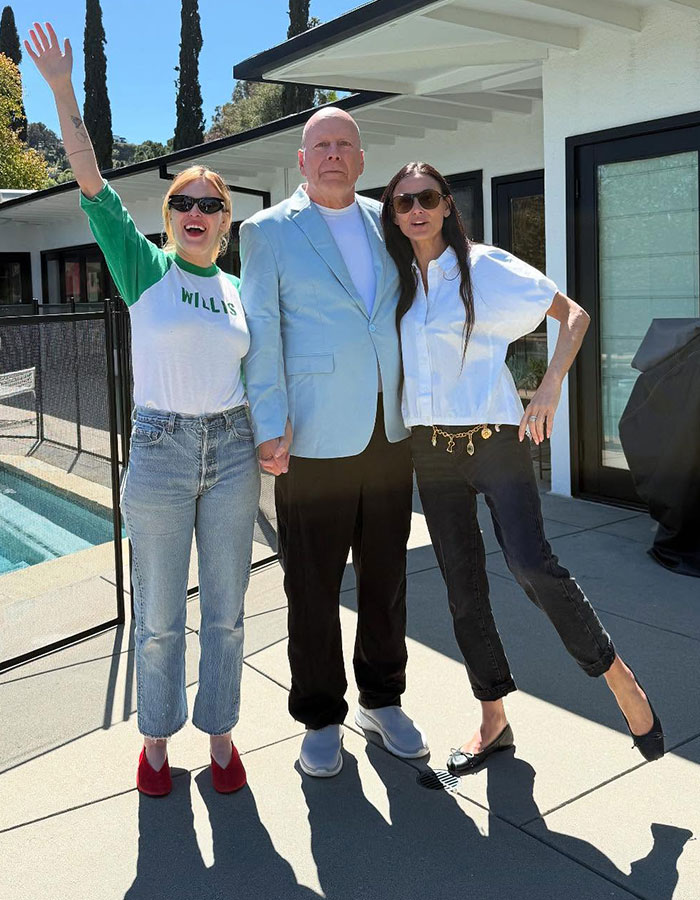 Bruce Willis with his daughter and another woman outside by a pool, all wearing sunglasses in casual attire. Bruce Willis with his daughter and another woman outside by a pool, all wearing sunglasses in casual attire.