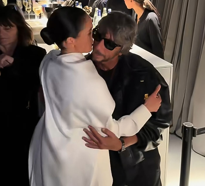 Meghan Markle embracing a man at Paris Fashion Week, with Balenciaga designer and attendees in the background.