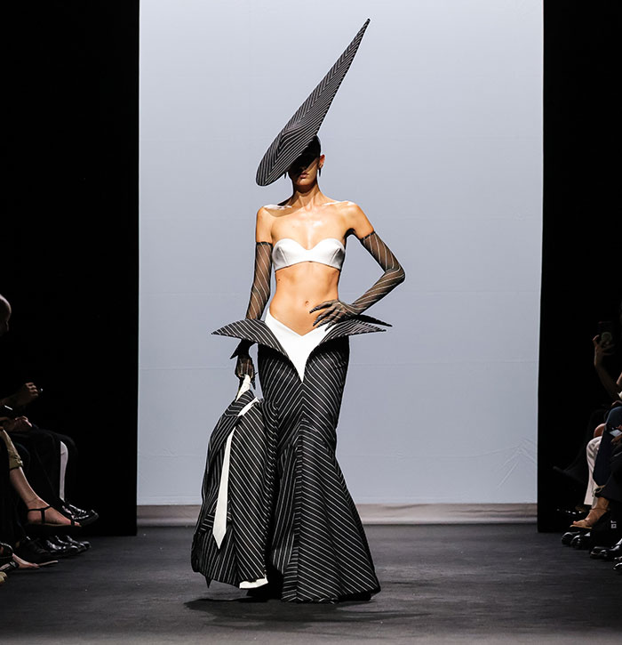 Model on runway wearing a dramatic avant-garde black and white outfit resembling Julia Fox&rsquo;s barely-there dress at a gala event.