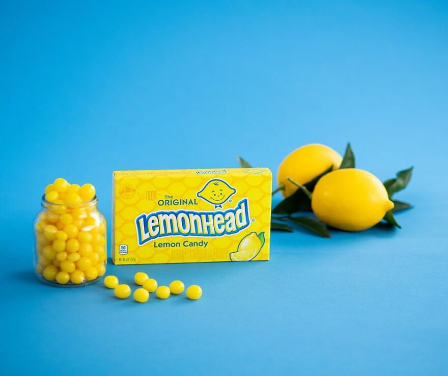 Lemonhead candy pack and jar with lemons on blue background representing popular Halloween candy 2025.