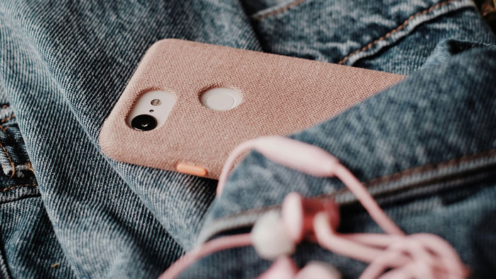 Smartphone with pink case resting on blue denim fabric, symbolizing people sharing worst crimes in their hometowns.