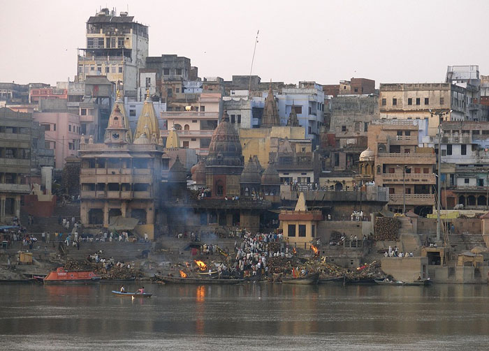 Crowded riverside with historic temples and old buildings, illustrating one of the places people wouldn’t revisit even if paid.
