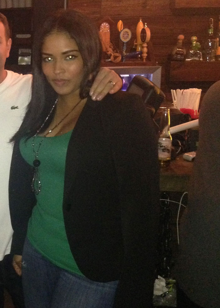 Woman in casual outfit standing in a bar, related to NYPD detective and mom of 3 found deceased after cosmetic surgery.