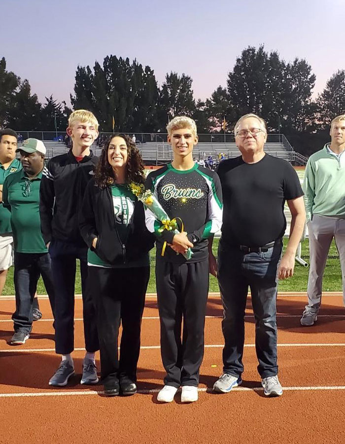 Missouri&rsquo;s first male homecoming queen stands with family on football field during evening event at Bruins game.