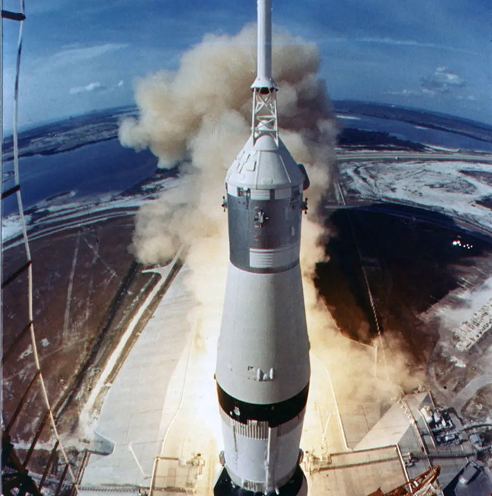 Saturn V rocket launching into space, relating to the 1969 moon landing and conspiracy discussions.