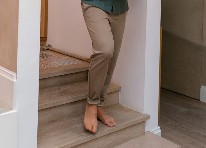 Person walking barefoot down wooden stairs inside a home, symbolizing endurance and strength from narcissistic mothers.