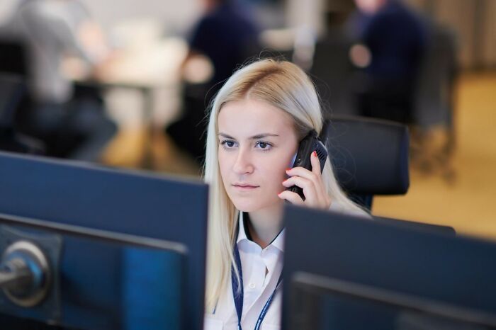 Woman focused on phone call and computer screens, illustrating moments of folks misreading social cues at work.