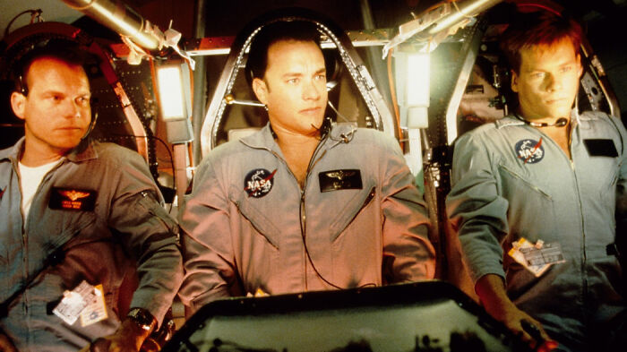 Three astronauts in a space shuttle cockpit wearing NASA suits, a scene from movies based on true stories.
