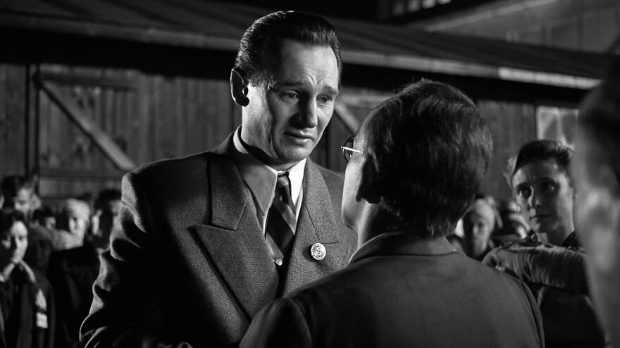 Black and white scene from a movie based on true stories showing intense conversation between two men in vintage clothing.