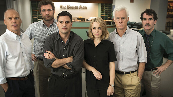 Cast members from a movie based on true stories that feel impossible to believe, posing in an office setting.
