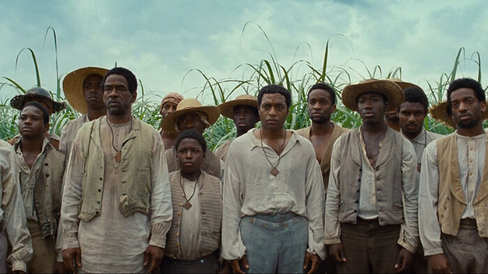 Group of men in period clothing standing in a field, representing scenes from movies based on true stories.