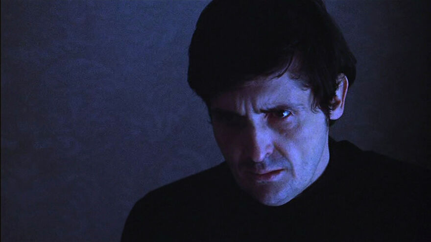 Close-up of a man in low light, portraying intense emotion in a scene from movies based on true stories.