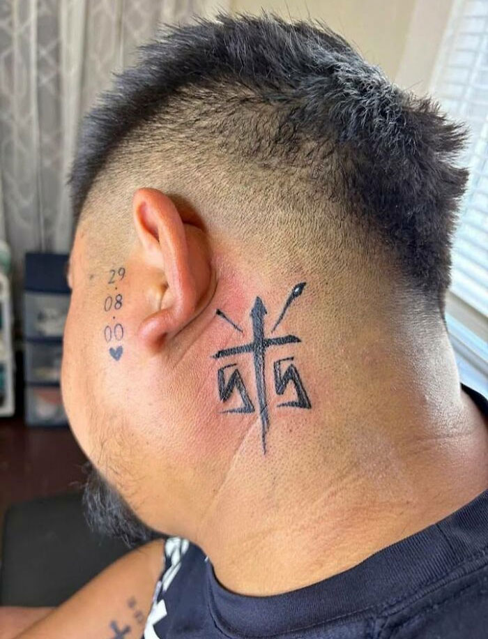 Tattoo of abstract symbols and numbers behind ear and on neck of a person, showing unique and bold body art choices.