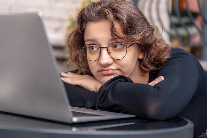 Young woman looking confused at laptop.