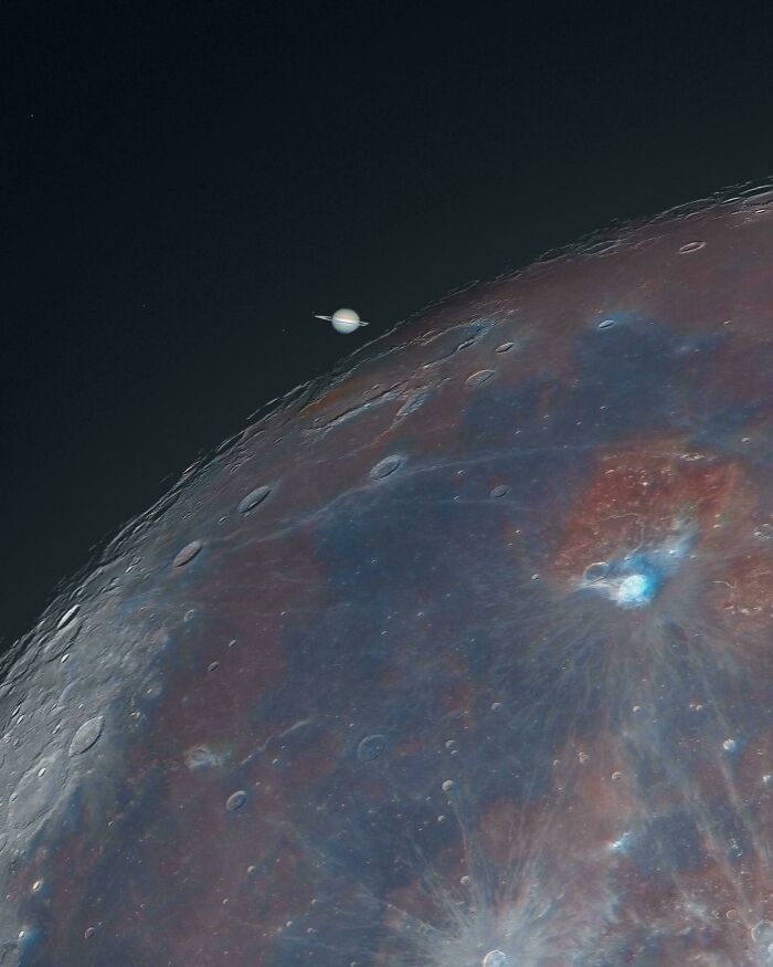 Close-up astronomy photo showing the detailed surface of the moon with Saturn visible in the background.