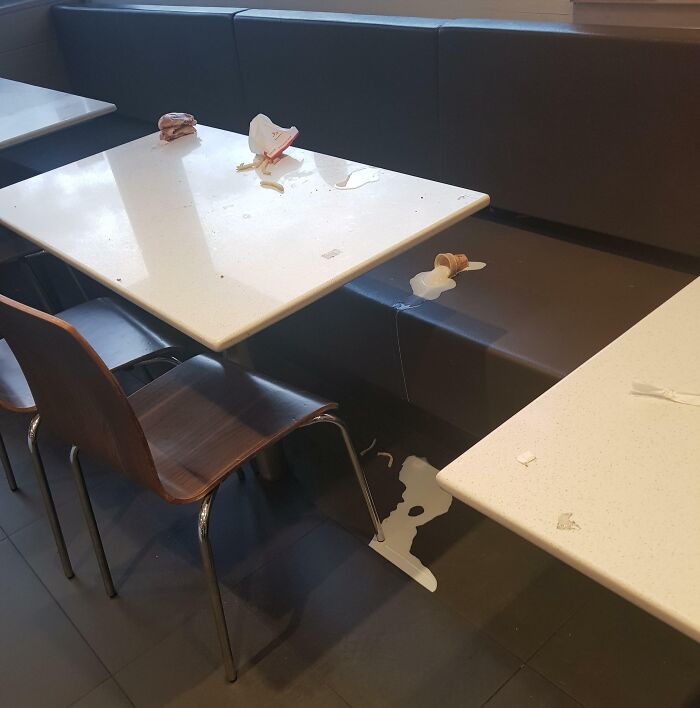 Messy fast food table with spilled milkshake and trash, showing people apparently allergic to acting like sensible adults.