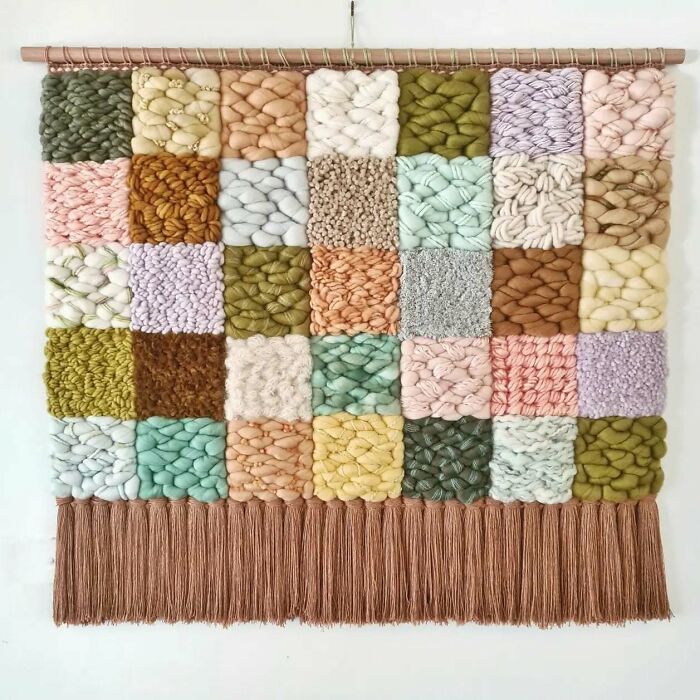 Colorful textile wall hanging featuring various textured squares made from threads in a mesmerizing artistic creation.