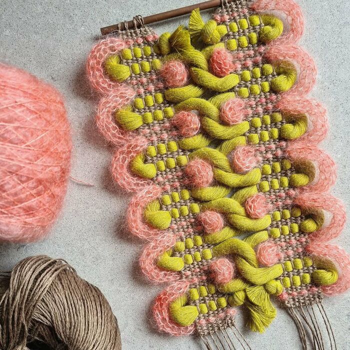 Intricate textile creation with pink and green threads woven into a mesmerizing, artistic fabric design.