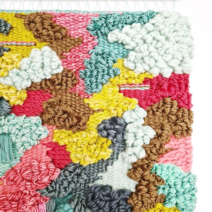 Colorful textured textile art featuring intricate thread work and vibrant yarn in an abstract woven creation.