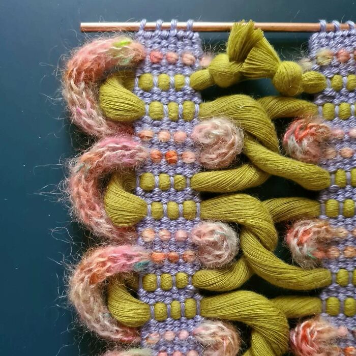 Close-up of mesmerizing textile creation with colorful threads woven into intricate patterns and textured loops on a blue background