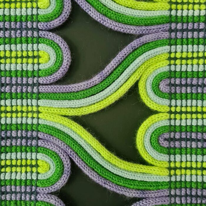 Close-up of mesmerizing textile creation featuring colorful knitted threads in green, yellow, and purple patterns.