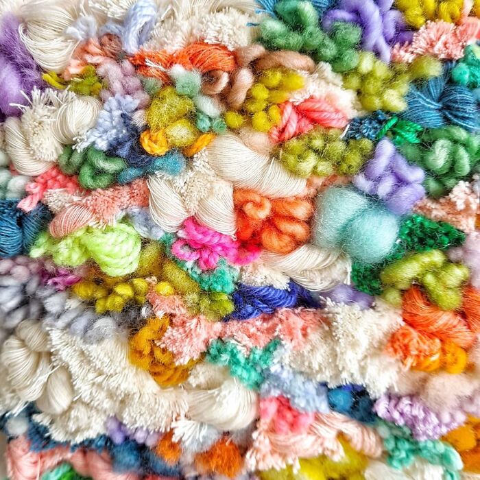Close-up of colorful textile creations showing intricate threads and textured weaving in an artistic, mesmerizing design.