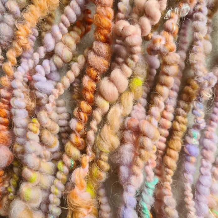 Close-up of colorful twisted threads showcasing mesmerizing textile creations by an artist with soft pastel hues and textures.