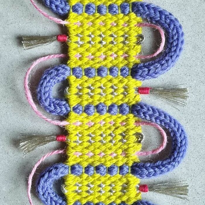 Mesmerizing textile creation featuring vibrant yellow and purple threads woven into an intricate and colorful pattern.