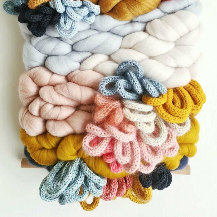Colorful textile creation featuring thick knitted threads woven into layered loops and braids, showcasing mesmerizing textile art.