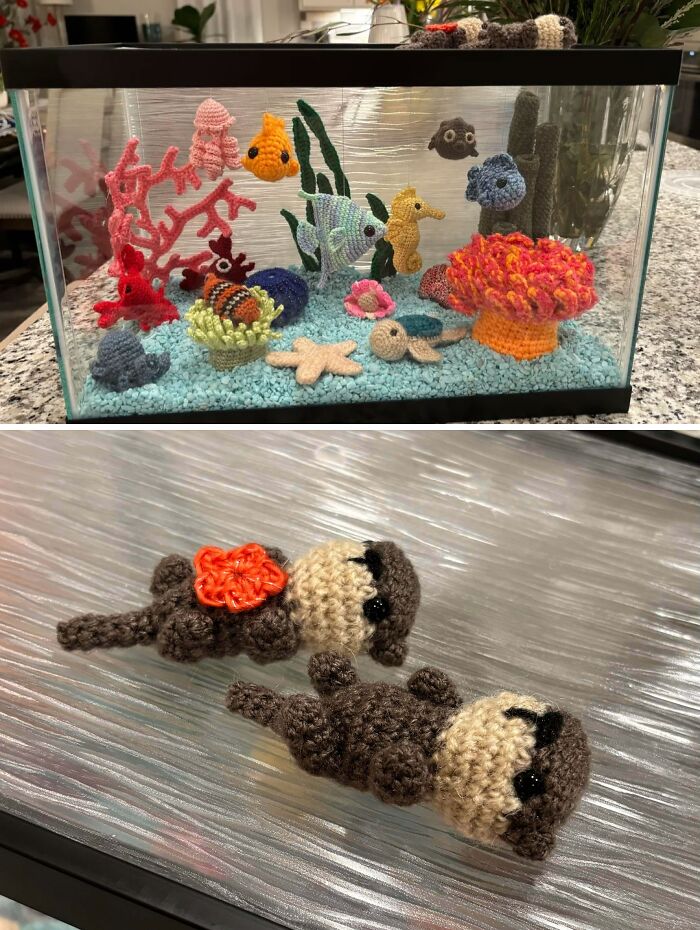 Crocheted underwater scene with colorful fish, coral, and sea creatures displayed inside a glass tank.
