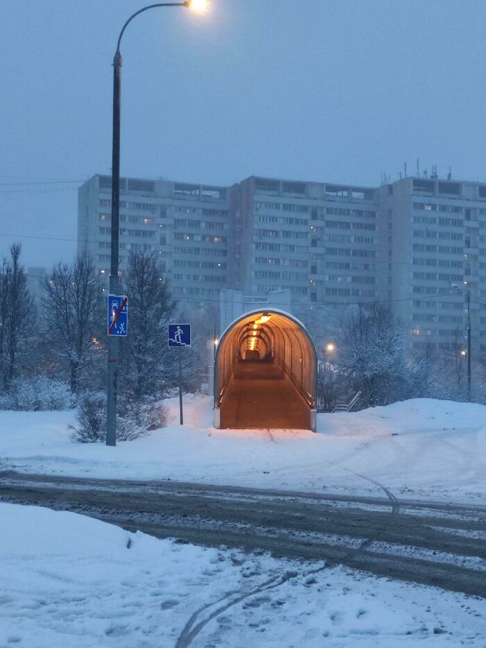 Snow-covered urban scene with a glowing tunnel entrance, appearing unphotoshopped but looking unreal and striking.