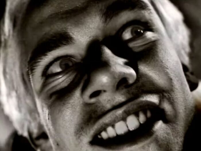 Close-up of a creepy man with wide eyes and a sinister grin, evoking the unsettling vibe of creepy commercials.