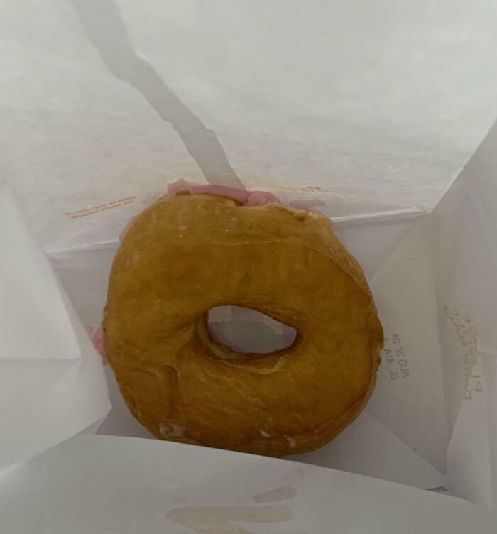 Glazed donut inside a paper bag showing a messy and humorous example of people allergic to acting like sensible adults.