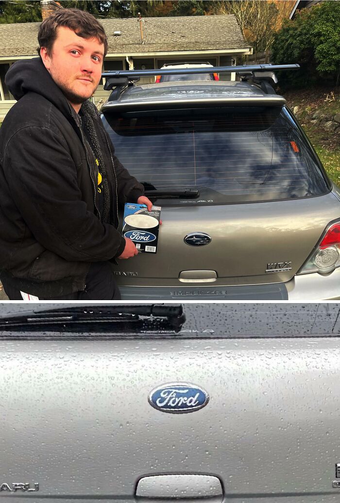 Man holding a Ford emblem sticker attaching it to a Subaru car, showcasing a clever and hilarious bumper sticker prank on the road.