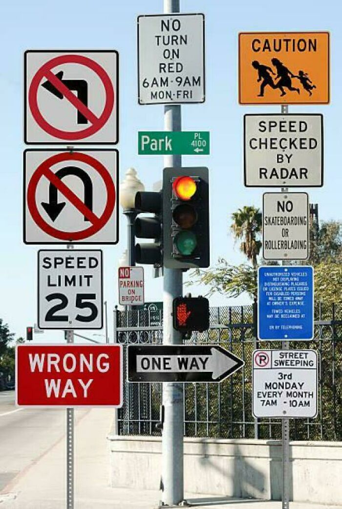 Multiple confusing road signs including no left turn, no U-turn, speed limit, wrong way, and one way creating traffic uncertainty.