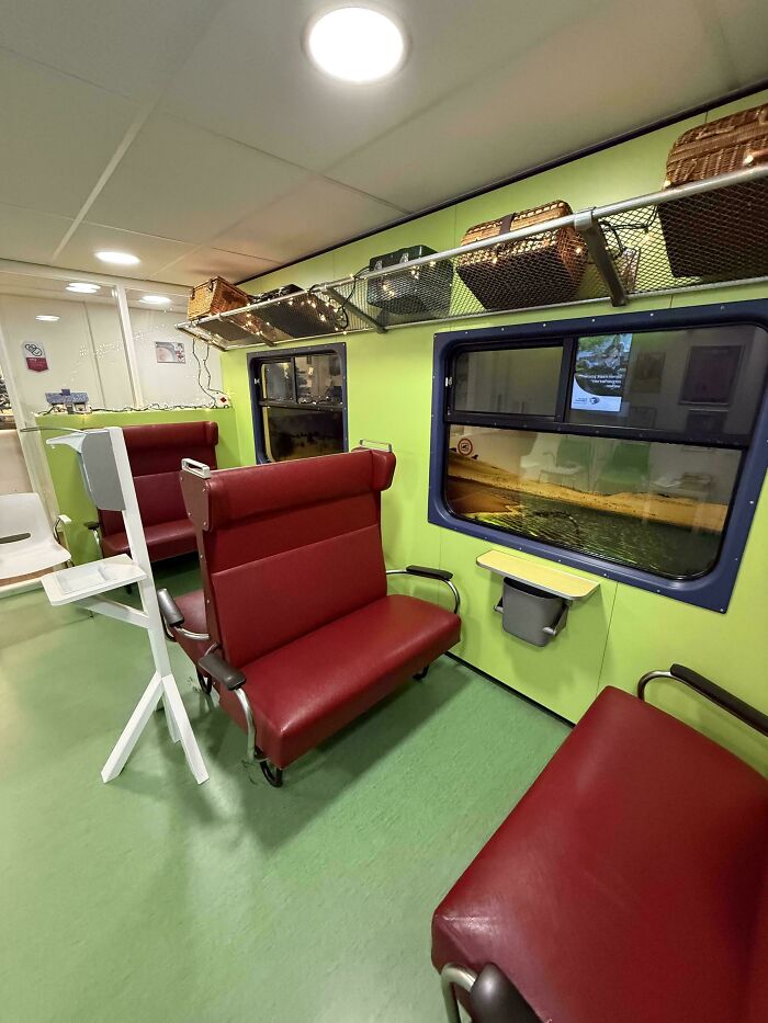 Medical waiting room designed like a vintage train compartment with cozy red seats to put patients at ease.
