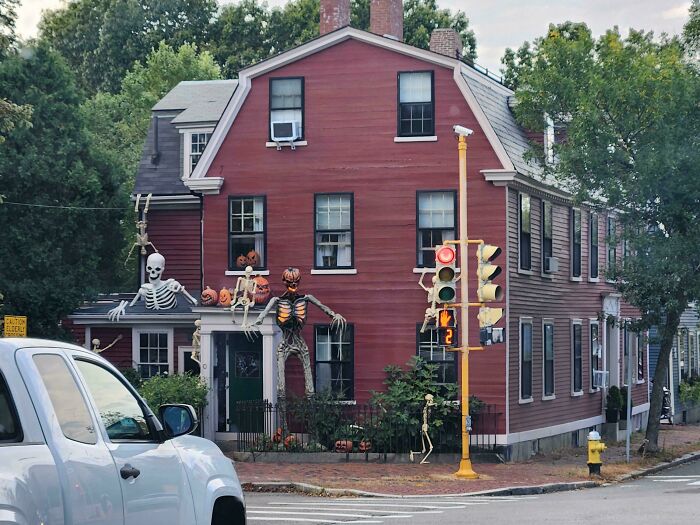 Large outdoor Halloween decorations with skeletons and pumpkins on a red house, showing creative outdoor Halloween decor pride.