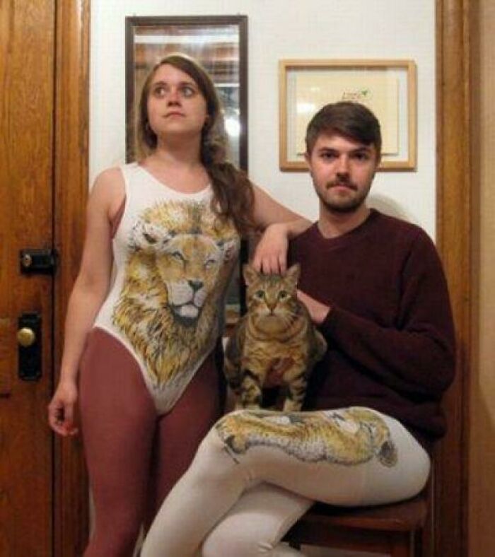 Couple and cat pose with matching lion-themed outfits in a funny family photo that became cringed at online forever.