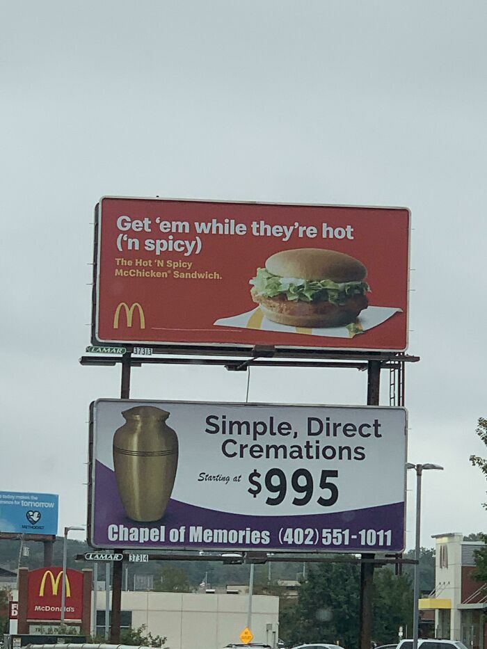 Funny and weird billboards featuring a McDonald's spicy sandwich ad above a cremation service promotion on a roadside structure.
