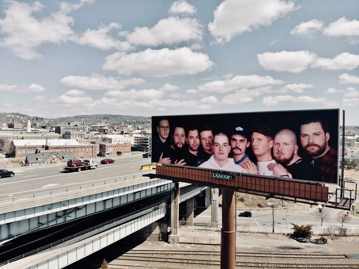 Billboard featuring a group photo of men on a highway, showcasing one of the funny and weird billboards paid for.