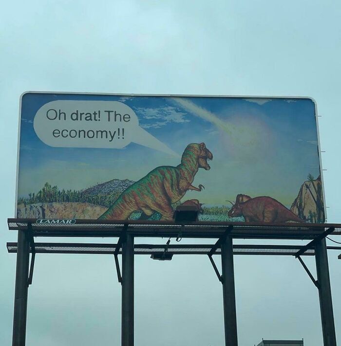 Funny and weird billboard featuring dinosaurs with a speech bubble about the economy and a meteor in the sky.