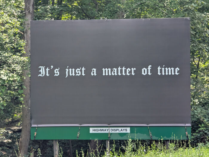 Minimalist black billboard with white gothic text that reads It's just a matter of time, a funny and weird billboard example.