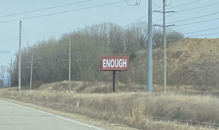 Billboard in a rural area with the word enough displayed, showcasing a funny and weird billboard concept.