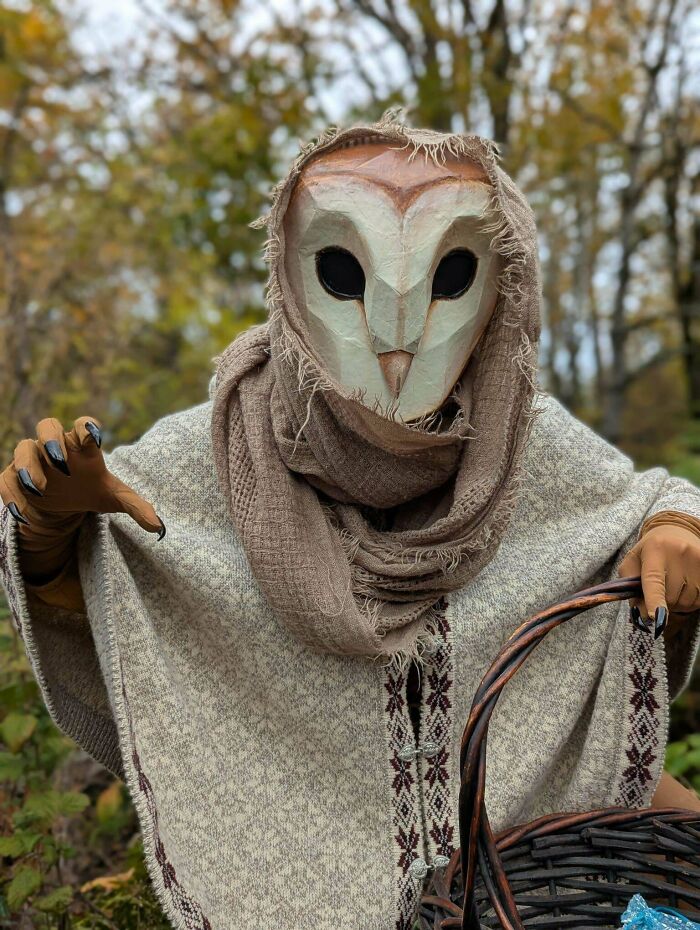Person wearing an owl mask and rustic costume holding a basket in a forest setting, creative Halloween costume idea.