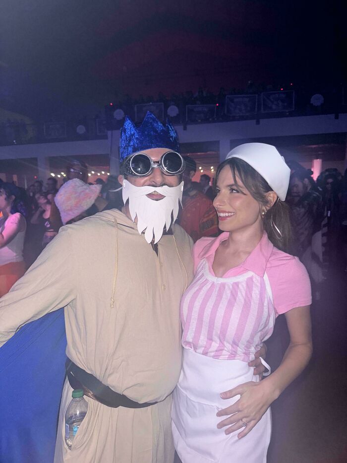 Couple dressed in genius Halloween costumes at a party, featuring a bearded king and a waitress outfit.