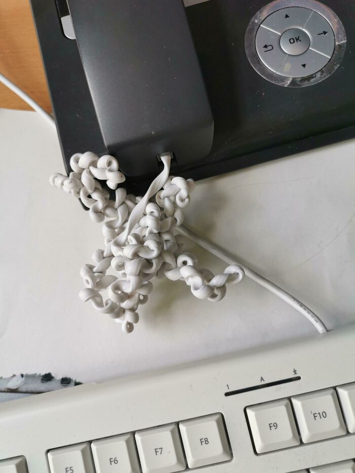 Curled and tangled telephone cord next to a keyboard, illustrating common painful electronics handling mistakes.