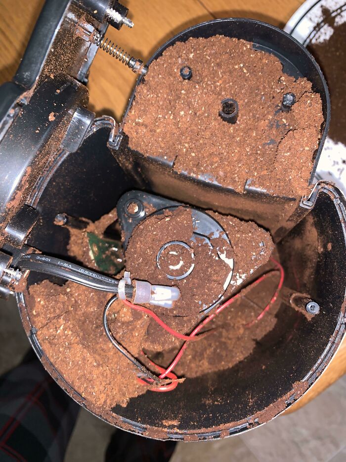 Coffee grounds spilled inside a broken electronic device showing improper handling of electronics and soldering issues.