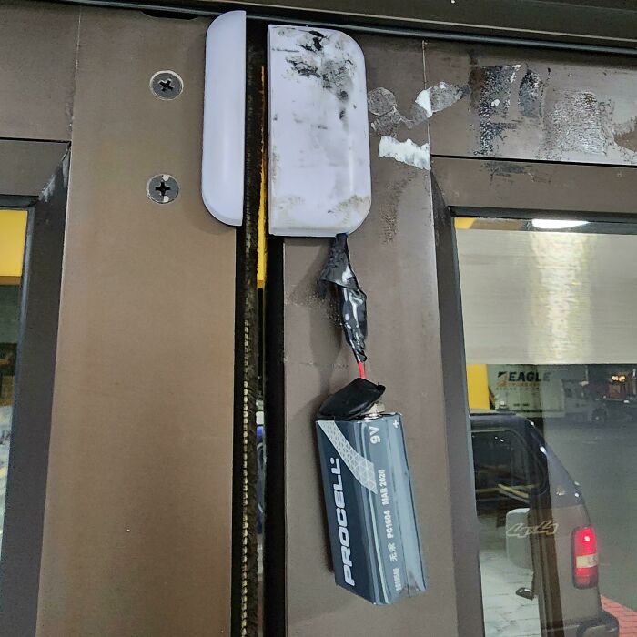 Improvised electronics repair with a leaking battery taped to a door sensor, showing a painful example of handling electronics the wrong way.
