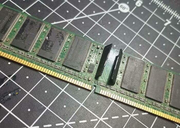 Broken RAM module snapped in half on a cutting mat, illustrating common mistakes in handling electronics the wrong way.