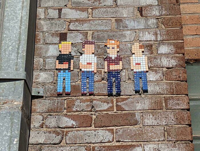 Pixelated street art of four characters on a brick wall showcasing beautiful and powerful street art from around the world.